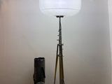 a lamp that is on a tripod next to a bag