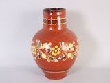 a red vase with a floral design on it
