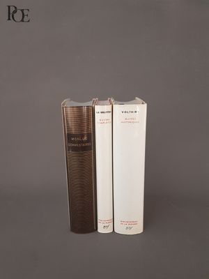 trois livres sont empilés sur une surface grise