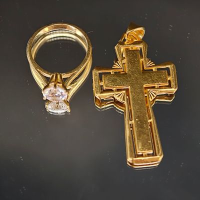 une croix en or et une bague en diamant posées sur une table