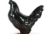 a black chicken statue on an orange base on a white background