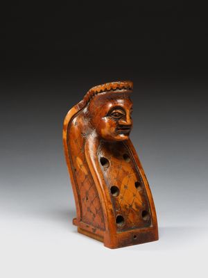 une vieille figurine en bois représentant une tête d'homme, posée sur un socle