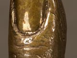 une figurine en bronze représentant la tête d'une femme posée sur une surface réfléchissante