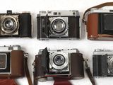 plusieurs vieux appareils photo sont alignés sur une surface blanche