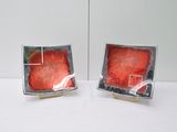 two red and black square dishes on a table