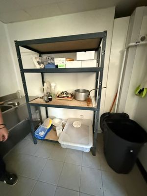 un homme debout dans une cuisine, à côté d'une poubelle