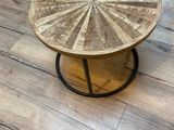 une table en bois avec un plateau rond posée sur un parquet
