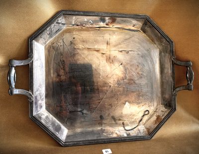 a silver tray with a handle on a gold cloth