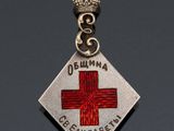 a close up of a silver and red cross charm on a black background