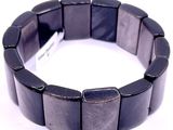 un bracelet noir muni d'une étiquette, posé sur une surface blanche