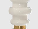 a close up of a lamp on a white surface with a gold base