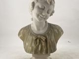 a white marble bust of a woman with a bow on her head