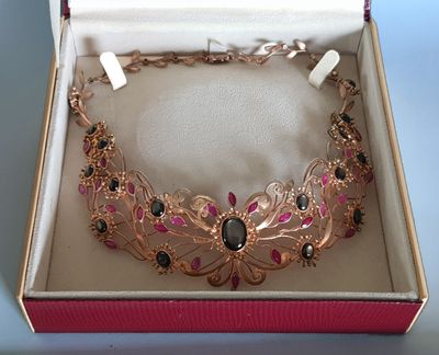 une boîte rose contenant un collier doré et noir