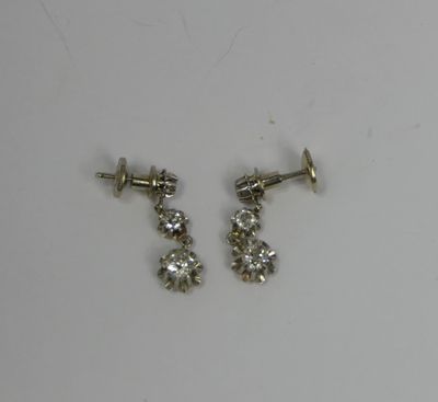 two pairs of diamond stud earrings on a white surface