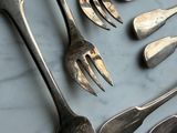 many forks and spoons laid out on a table
