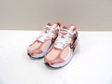 chaussures de course Nike Air Presto roses et blanches posées sur une surface blanche
