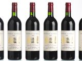 six bottles of red wine lined up in a row on a table