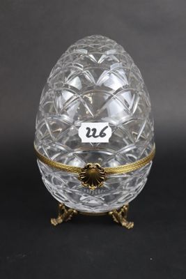 an egg shaped glass box with gold trimming and a label on it