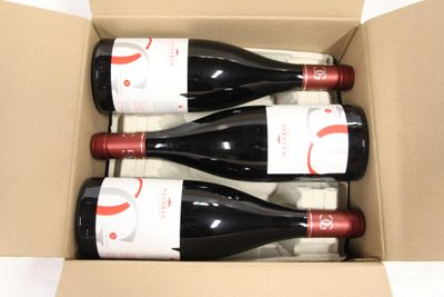 three bottles of red wine in a cardboard box on a white surface