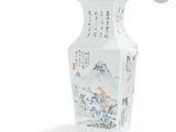 un vase blanc avec un tableau posé sur une table