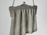 silver metal mesh purse with chain strap hanging from a chain