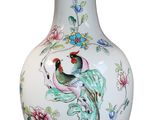 a white vase with a bird and flowers on it