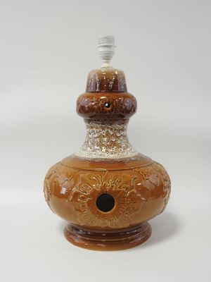 un vase marron avec un couvercle blanc et un socle marron