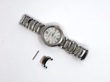 a watch that is laying on a white surface next to a piece of metal