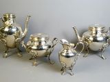three silver teapots and a coffee pot on a table