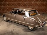 a brown car that is parked in front of a brick wall