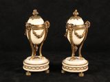 two white and gold vases sitting on top of a black surface