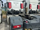 Plusieurs semi-remorques sont garées sur un parking, avec un bâtiment en arrière-plan.