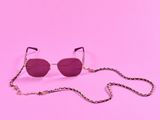 une paire de lunettes de soleil avec une chaîne, sur fond rose