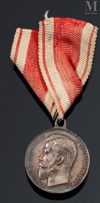 une vieille médaille ornée d'un ruban rouge et blanc sur un fond noir