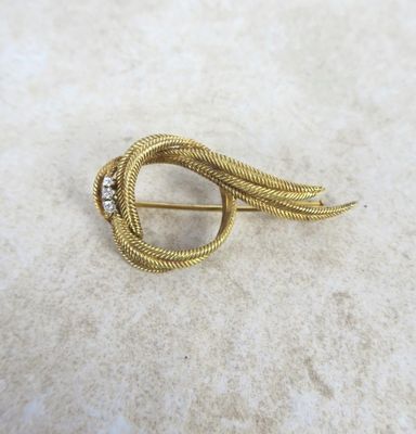 a close up of a gold brooch with a diamond on it