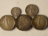 six different coins are arranged in a row on a white surface