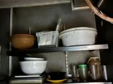 many bowls and pans on the shelves in the kitchen