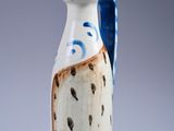 a white and blue vase with a blue handle on it