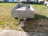 a trailer that is sitting in the grass by some cars