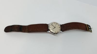 gros plan d'une montre sur une surface blanche avec un bracelet marron