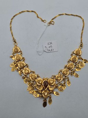 a gold necklace with leaves and flowers on it