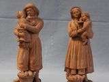 two wooden figurines of a woman holding a baby and a child