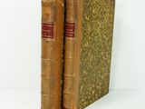 two old books sitting on top of each other on a white surface