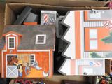 a cardboard box filled with assorted toys and a doll house