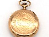 une montre de poche en or sur une surface blanche