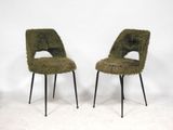two green chairs with black legs and a white wall in the background