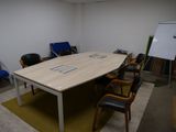 des tables et des chaises dans une pièce où se trouve un tableau blanc accroché au mur