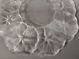 a clear glass plate with flowers on it on a table