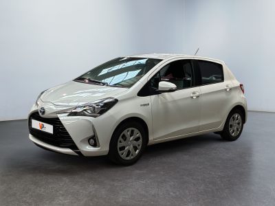une Toyota Yaris blanche garée dans une pièce au sol noir