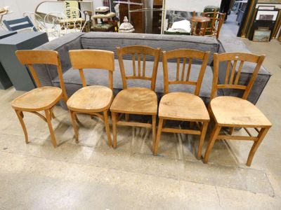 six wooden chairs in a room with a couch in the background